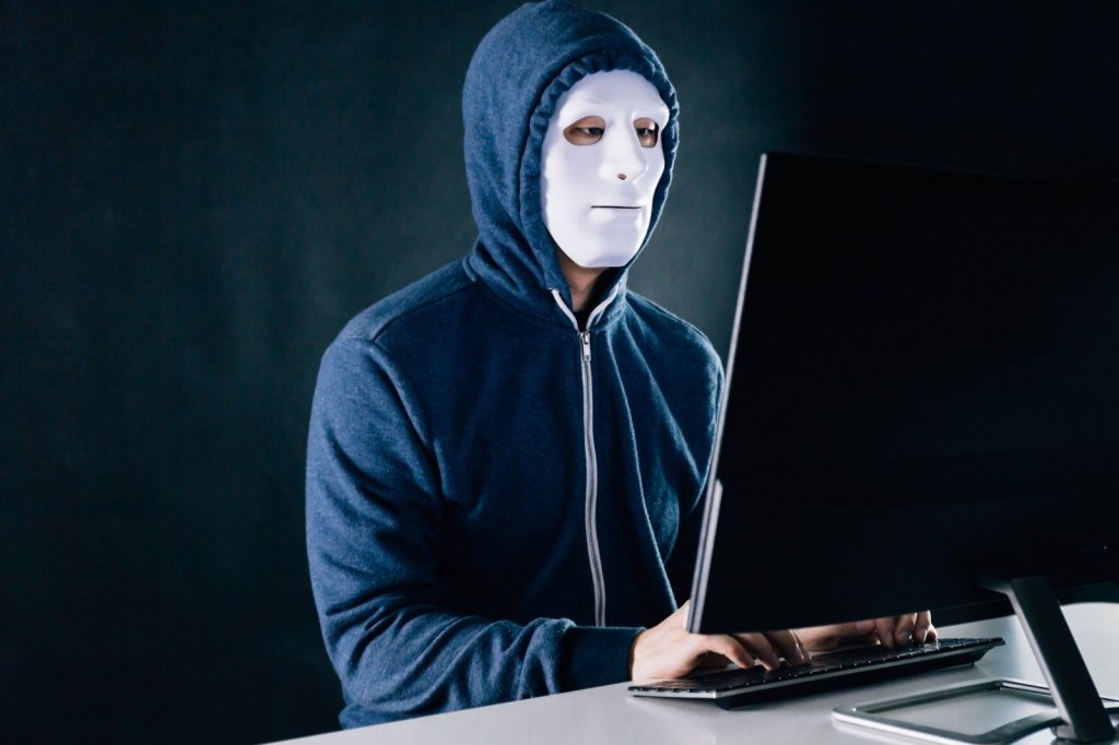 A masked person using a computer.